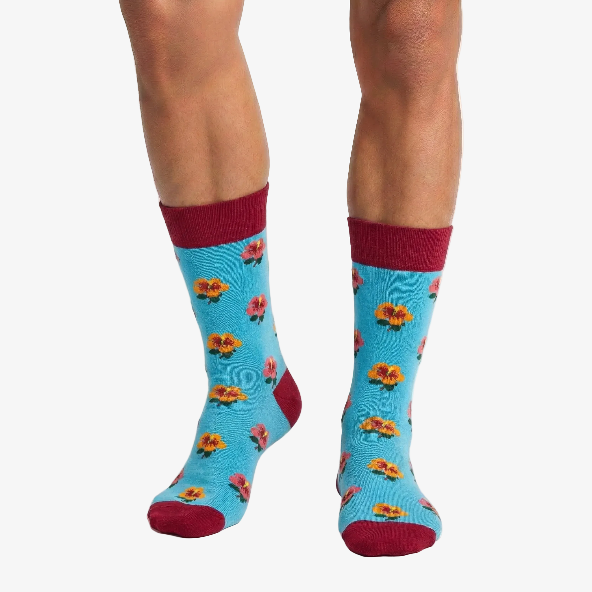 Blue socks with floral pattern and red cuffs and toes worn by a person on a white background